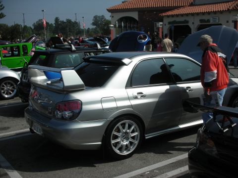 1998 Ford Crown Victoria - Silver Subaru Impreza WRX STI with aftermarket wheels and spoiler at a car meet.