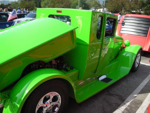 1998 Ford Crown Victoria - A bright green custom truck is parked next to a red vehicle at an outdoor gathering.