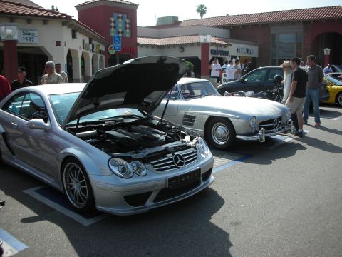 1998 Ford Crown Victoria - A silver Mercedes-Benz CLK is parked with its hood open, revealing the engine, next to a classic silver Mercedes-Benz.