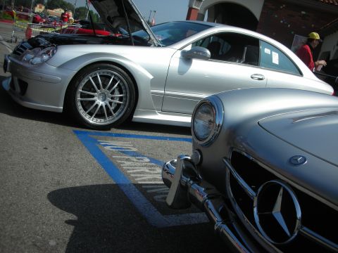 1998 Ford Crown Victoria - Two silver Mercedes-Benz cars are parked side-by-side, one with its hood open.