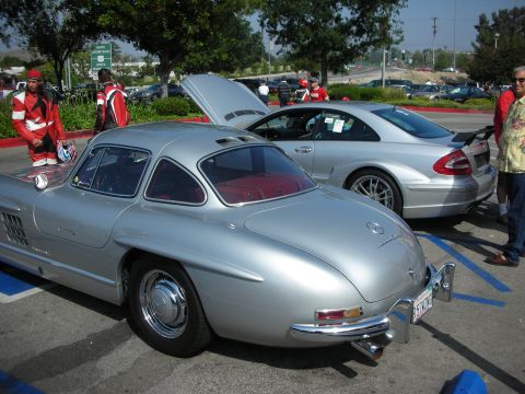 1998 Ford Crown Victoria - A classic Mercedes-Benz 300 SL Gullwing is parked next to a modern silver coupe at an outdoor gathering.