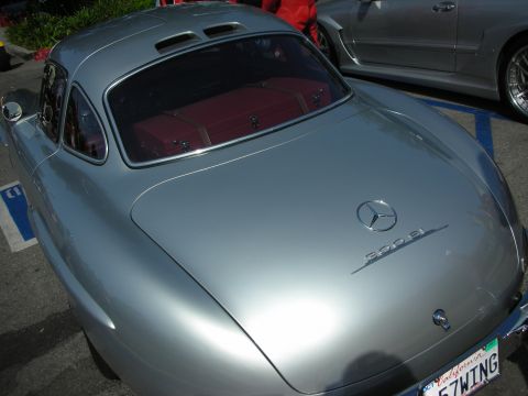 1998 Ford Crown Victoria - A classic silver Mercedes-Benz 300 SL Gullwing is parked next to another car.