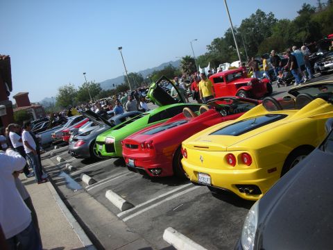 1998 Ford Crown Victoria - A line of sports cars, including a yellow Ferrari, are parked at an outdoor event.