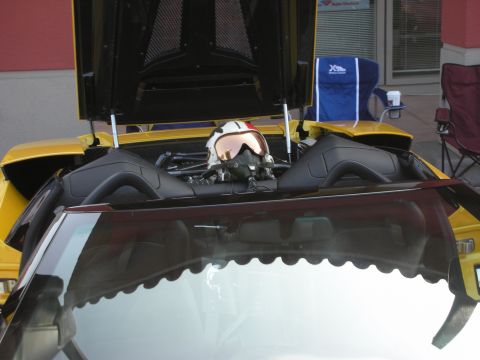 1998 Ford Crown Victoria - A pilot's helmet is placed on the engine of a yellow sports car.