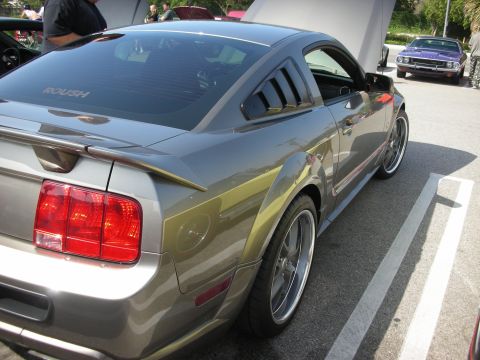 1998 Ford Crown Victoria - A gray Roush Mustang is parked at a car meet, with a purple muscle car visible in the background.