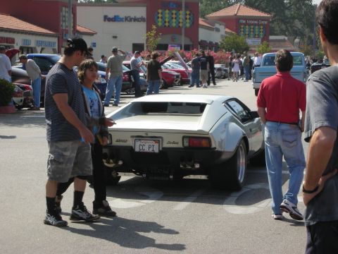 1998 Ford Crown Victoria - A group of people admire a classic De Tomaso Pantera at an outdoor car meet.
