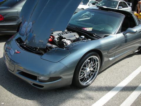 1998 Ford Crown Victoria - A gray Chevrolet Corvette C5 is parked with its hood open, revealing the engine compartment.