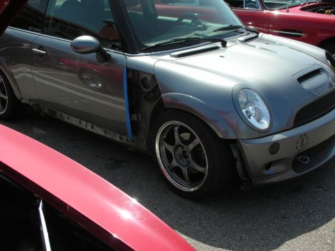 1998 Ford Crown Victoria - A gray Mini Cooper is parked next to a red car, with its front fender and door panel removed.