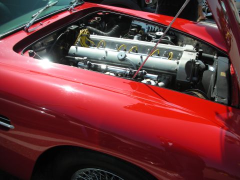 1998 Ford Crown Victoria - The engine bay of a red car is open, revealing its inline-six engine and yellow spark plug wires.