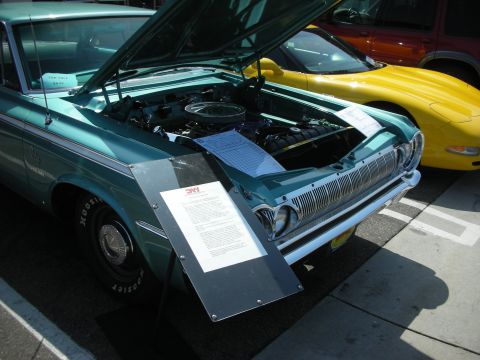 1998 Ford Crown Victoria - A teal 1965 Dodge Polara is displayed with its hood open, parked next to a yellow Chevrolet Corvette at a car show.