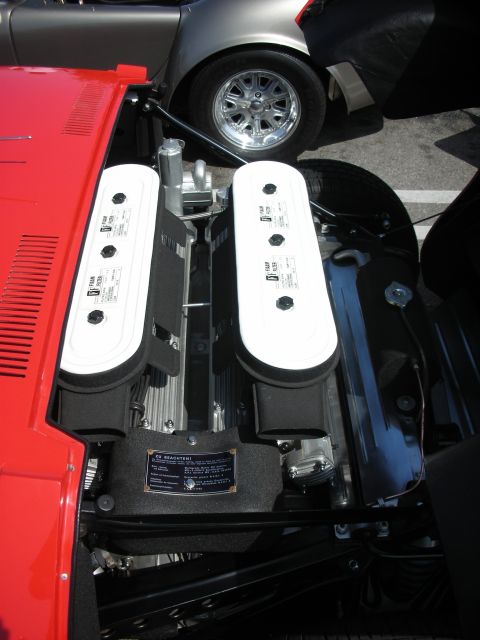 1998 Ford Crown Victoria - The engine bay of a red car is shown, with a silver car visible in the background.
