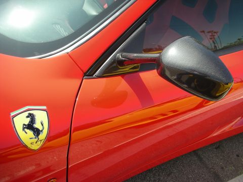 1998 Ford Crown Victoria - Close-up of a red sports car's fender, the iconic Ferrari badge and a carbon fiber side mirror.