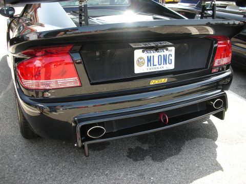 1998 Ford Crown Victoria - The rear of a black sports car is shown, a prominent spoiler and dual exhaust pipes.