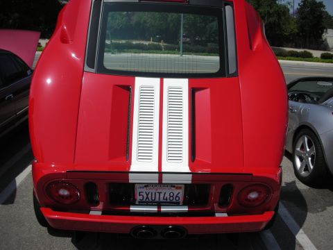 1998 Ford Crown Victoria - Rear view of a red sports car with white racing stripes and dual exhaust pipes.