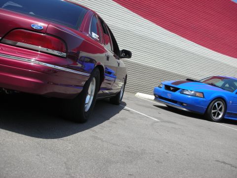 1998 Ford Crown Victoria - Two Ford vehicles, a Crown Victoria and a Mustang, parked side-by-side.