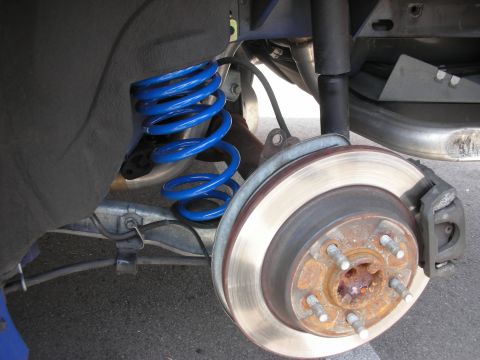 1998 Ford Crown Victoria - Close-up of a vehicle's rear suspension system, a blue coilover and brake components.