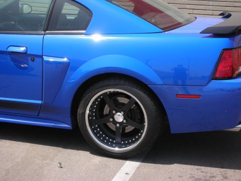 1998 Ford Crown Victoria - A blue Ford Mustang is shown from the side, highlighting its custom wheels and racing stripes.