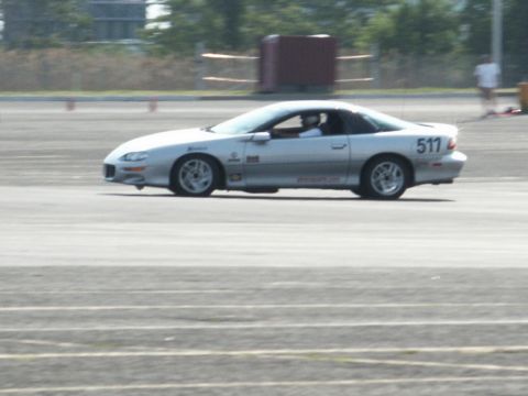 2001 Mercury Grand Marquis - A silver Chevrolet Camaro Z28, likely from the late 1990s, is captured in motion on a race track, displaying racing decals and the number 5…