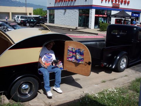 1972 Ford Ranchero - Man sits in a custom trailer hitched to a black pickup truck in front of a Firestone store.