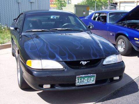 1972 Ford Ranchero - Black Ford Mustang with custom flame graphics and a blue Chevrolet Camaro in the background.