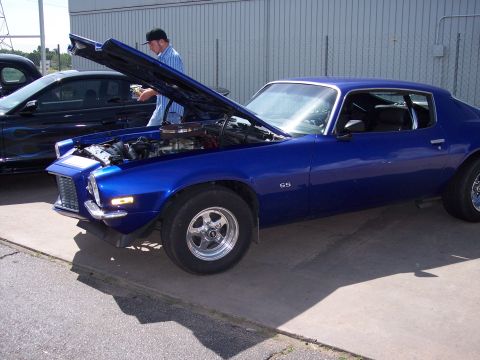 1972 Ford Ranchero - A blue Chevrolet Camaro SS is parked with its hood up, next to a car with flame decals.