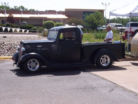 1972 Ford Ranchero - A classic black pickup truck from 1935 is parked outdoors, a distinctive body style and chrome wheels.