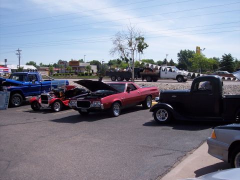 1972 Ford Ranchero - Several vehicles are parked in a lot, including a red Ford Ranchero with its hood up.