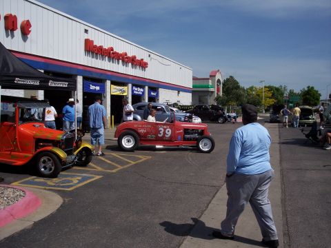 1972 Ford Ranchero - Several vintage and custom cars are on display outside a MasterCare Car Service building on a sunny day.