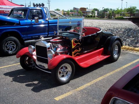 1972 Ford Ranchero - A custom hot rod roadster with flame decals is parked in a lot next to a blue pickup truck.