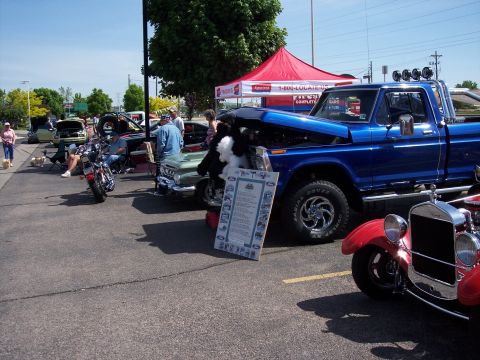 1972 Ford Ranchero - A blue pickup truck and a red vintage car are displayed at an outdoor event with a red tent in the background.