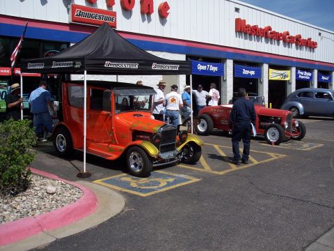 1972 Ford Ranchero - An orange hot rod with flame decals and gold fenders is displayed under a black tent at an outdoor event.