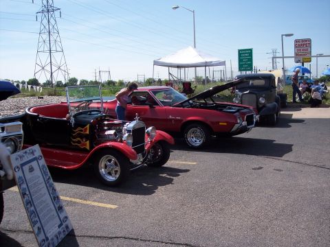 1972 Ford Ranchero - A red 1970s coupe and a red hot rod are parked side-by-side at an outdoor event.
