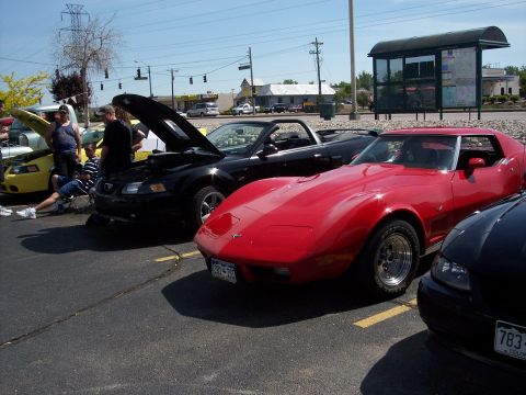 1972 Ford Ranchero - Several cars are parked in a lot on a sunny day, including a red sports car and a black convertible with its hood up.
