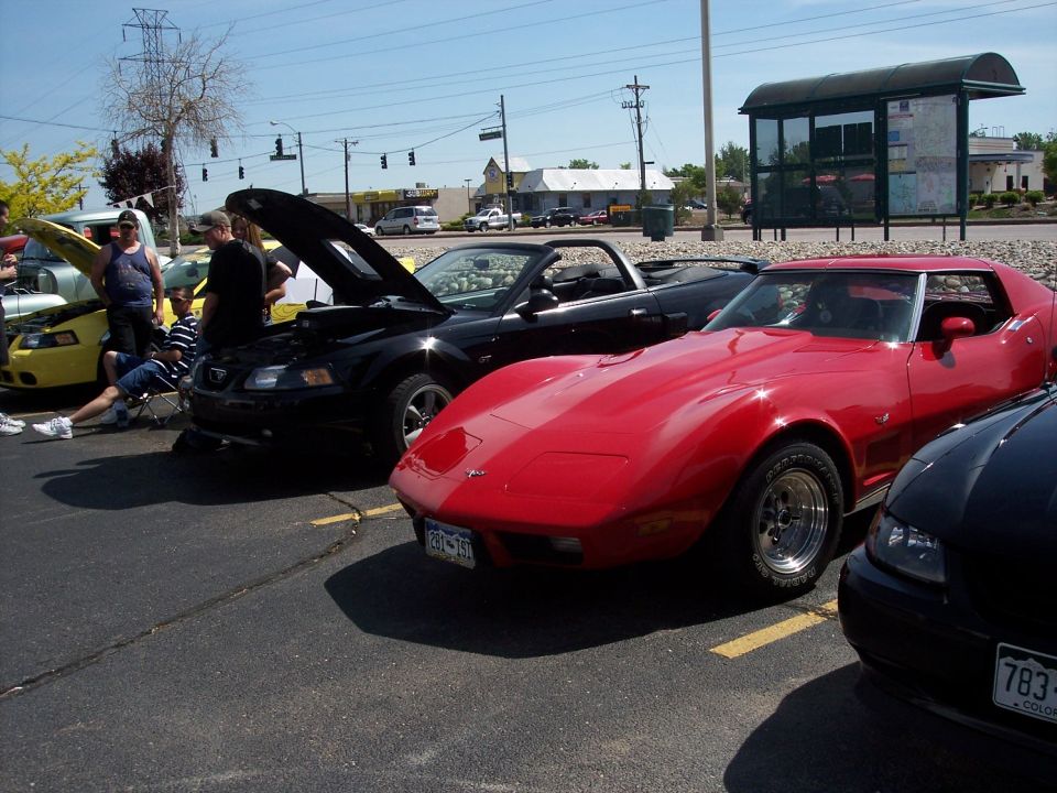 Red sports car and black convertible parked in a lot. License plate on red car reads 293-JSI