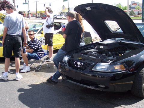 1972 Ford Ranchero - A black Ford Mustang is displayed with its hood open, the engine bay. Another car is visible in the background.