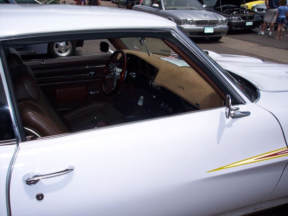 White classic coupe side window view of brown interior with wood-rim steering wheel