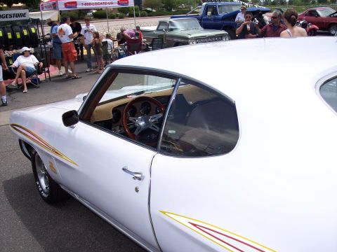 1972 Ford Ranchero - A white coupe with distinctive racing stripes is parked at an outdoor event with other vehicles and spectators.