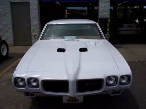 1972 Ford Ranchero - A white 1970 Pontiac GTO is parked in front of a garage, showing its distinctive front end.