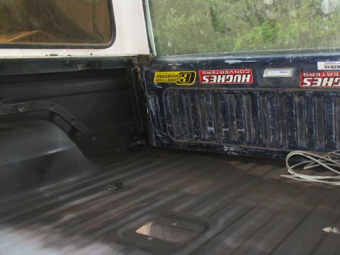 1978 Ford Bronco - The interior of a truck bed shows various stickers on the tailgate, including "Hughes Converters" and "Competition Engineering."