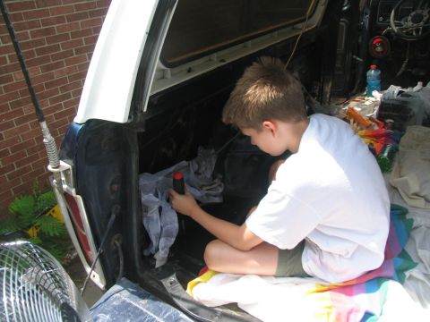1978 Ford Bronco - A young boy works on the interior of a vehicle, with the rear cargo area and some tools visible.