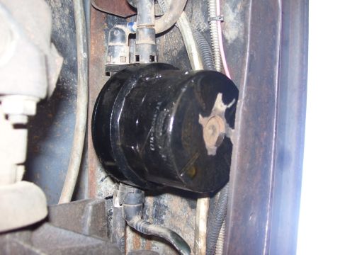 1986 Ford Bronco - Close-up of a black cylindrical automotive part with attached hoses, showing part number E7TA-2C044-AA.