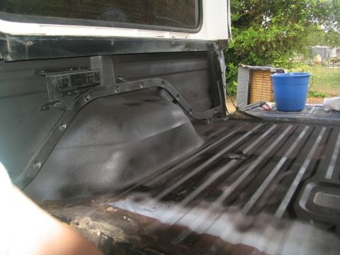1978 Ford Bronco - The interior of a truck bed is shown with black primer applied to the wheel well and floor.