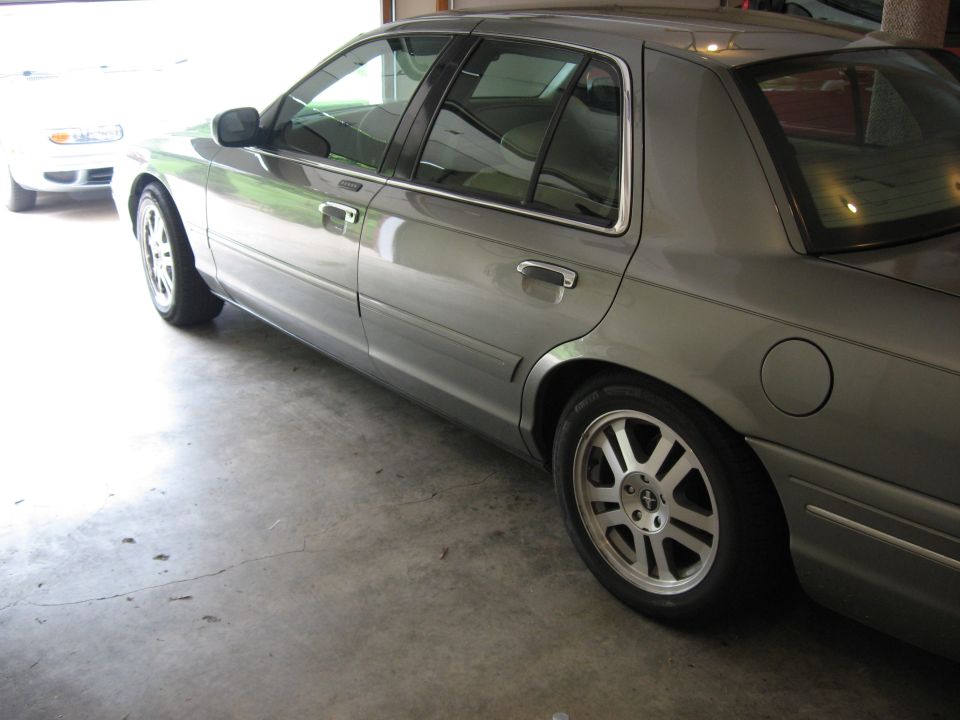 Silver-green Ford Crown Victoria rear three-quarter view in garage with alloy wheels