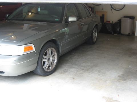 2001 Ford Crown Victoria - Gray 2001 Ford Crown Victoria in a garage, showing front quarter panel and wheel.