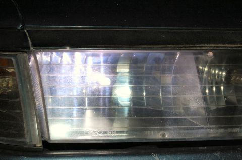 1985 Mercury Grand Marquis - Close-up of a headlight assembly, showing the Ford logo and part number etched into the lens.
