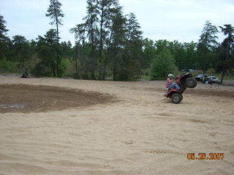 2000 Chevrolet Tahoe - An ATV is shown performing a wheelie on a sandy terrain with trees in the background.