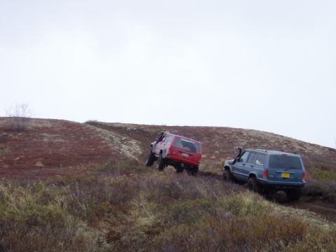 2000 Ford E350 - Two Jeep Cherokees navigate a challenging off-road course on a cloudy day.