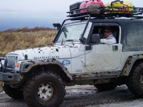 2000 Ford E350 - Mud-covered Jeep Wrangler Rubicon equipped for off-road adventure with extra fuel and equipment.