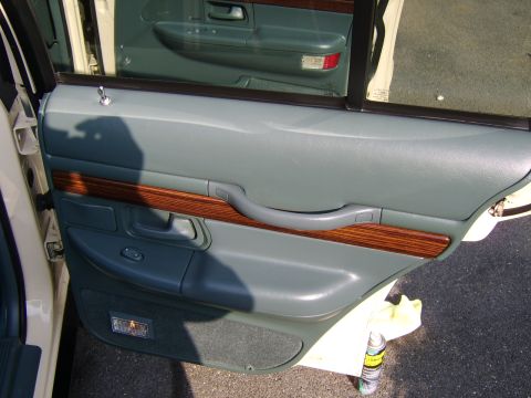 1996 Mercury Grand Marquis - Close-up of a car's interior door panel, wood grain accents and gray upholstery.