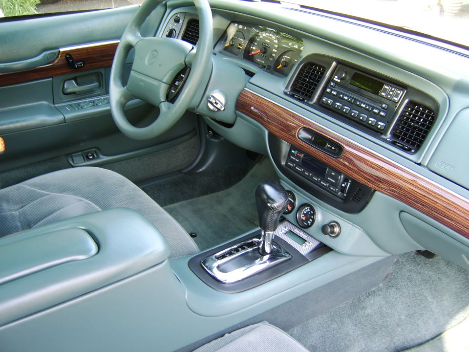 Teal-green car interior with woodgrain dash, steering wheel, and console shifter